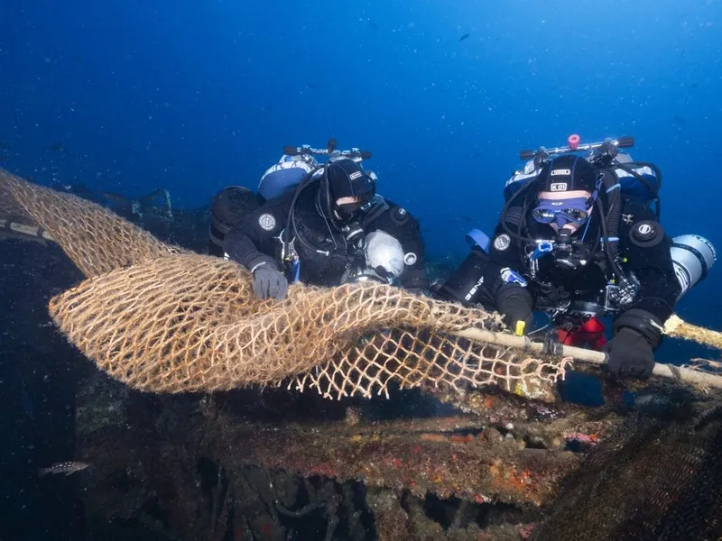 Trawl netting draped over the Midnight Hour wreck as divers begin removal